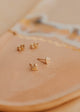 Gold heart-shaped earrings on a beige surface