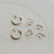 Set of silver hoop earrings on a light beige background