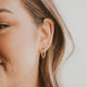 Thick gold hoops styled in an ear with small gold hoop earring and twist earrings by Hello Adorn in 14k gold fill.