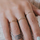 Learn how to stack rings on fingers with Hello Adorn with this 14k gold fill ring stack using two thin hammered rings, two thin ring bands, and a chain ring shown on a model.