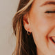 Small gold hoop earring by Hello Adorn shown styled in a model's ear in an infinity hoops style.