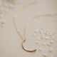 A crescent moon pendant attached to a dainty chain necklace created by Hello Adorn, this mini-moon necklace is perfect to finish a necklace layering look.