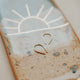 14k gold fill tiny horseshoe threader earrings by Hello Adorn laid flat on a sun design jewelry tray